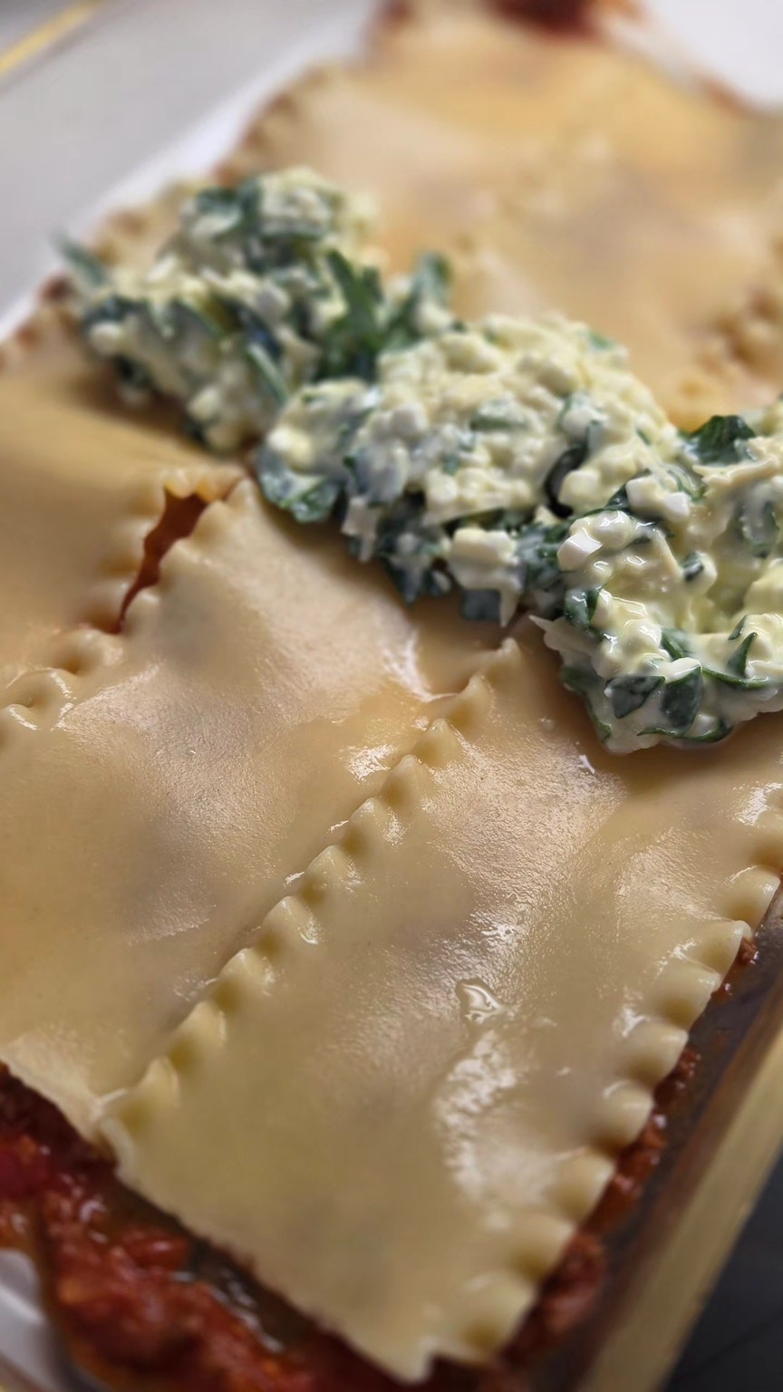 Signature cheese and spinach mixture being added between lasagna layers